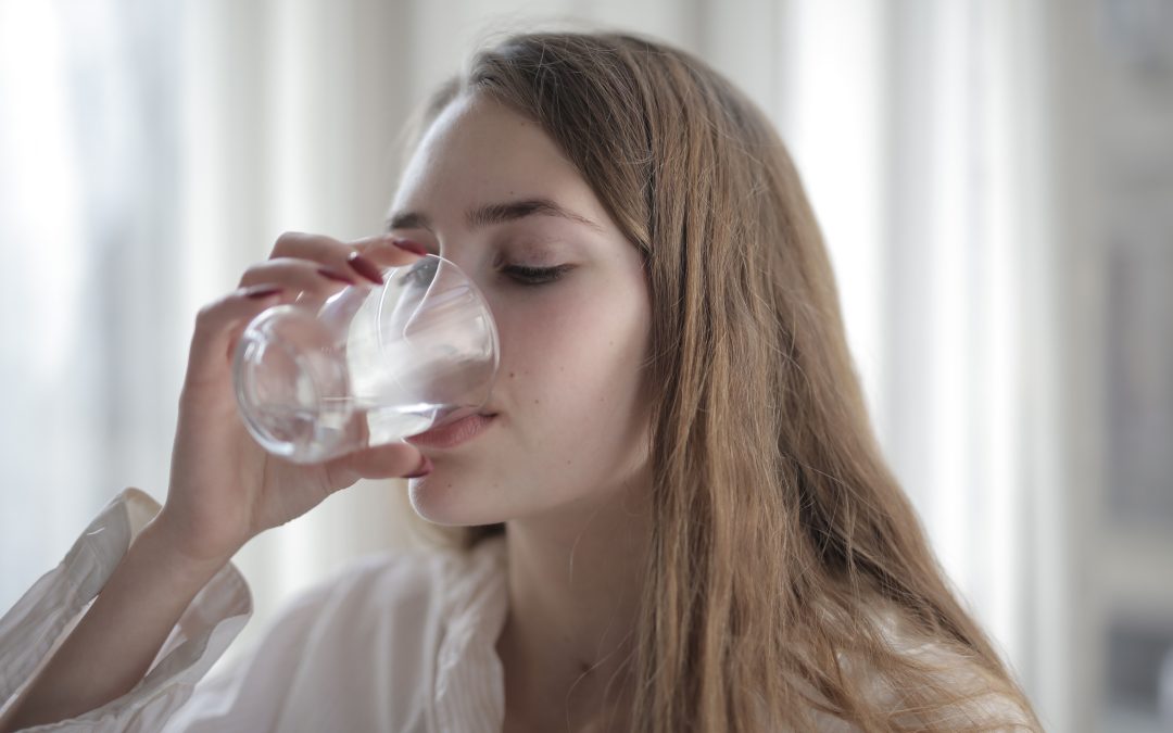 Woman drinking a glass of water to support digestion and relieve constipation