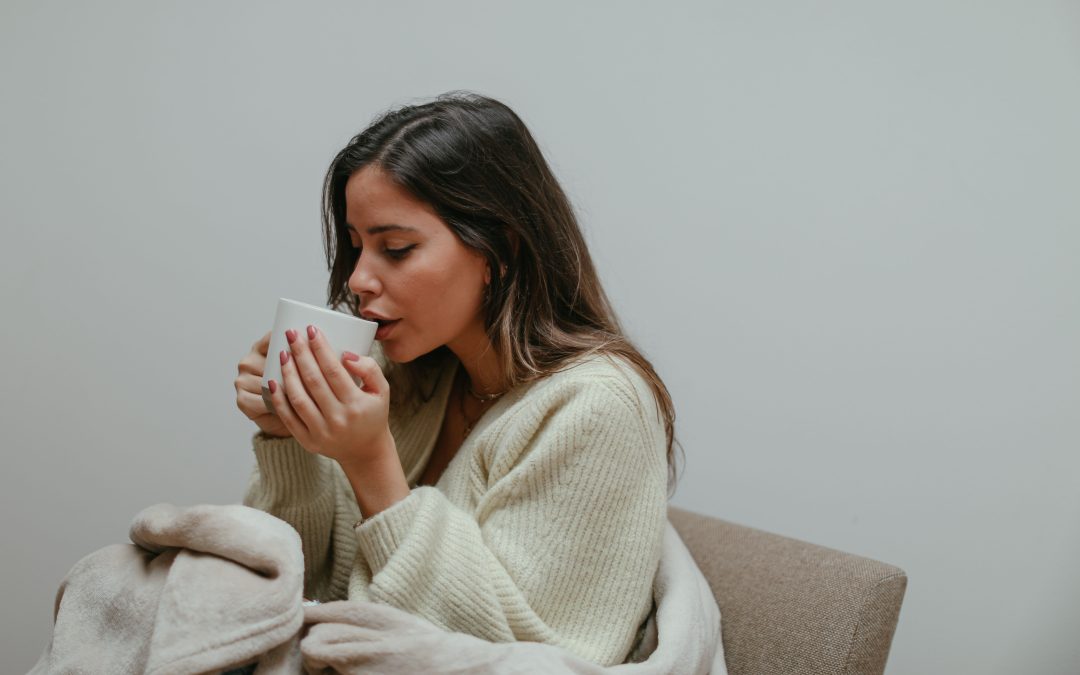 Woman drinking warm tea to soothe a cough at home