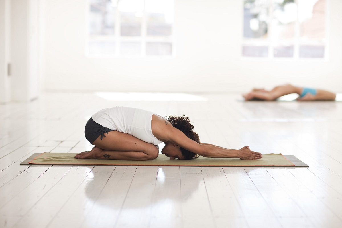 seated meditation posture on a plain mat, side view · timeline graphic showing the five historical periods of yoga · open Sanskrit text with English translation beside it